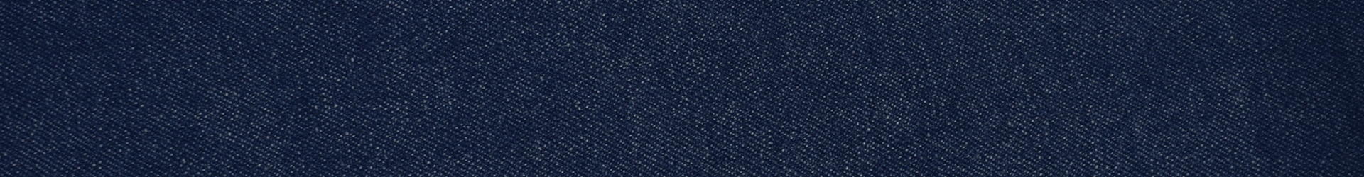 Close-up texture of dark indigo blue denim fabric showing the diagonal twill weave pattern with small white flecks throughout. No people, text, or other elements are present in the image.