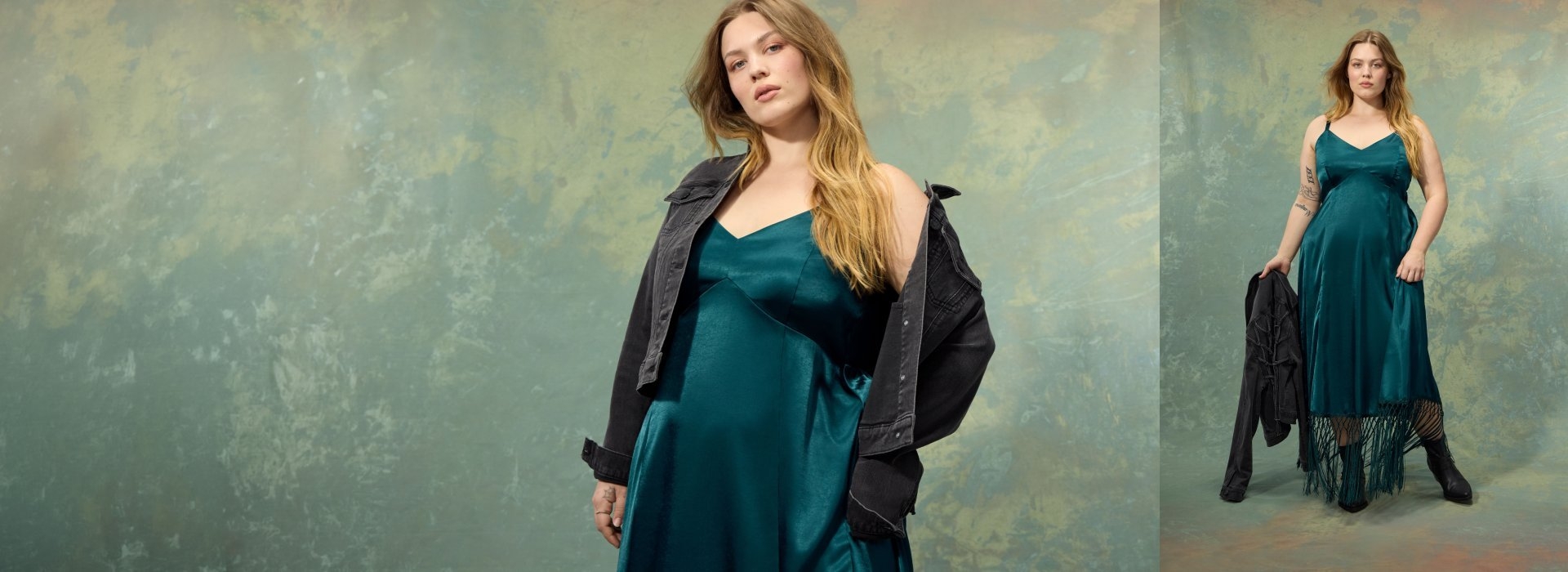 A two panel composite image with a mottled green and gold textured background in both. In the left panel, a woman with long wavy strawberry blonde hair wears an off-shoulder black denim jacket over a satin teal green slip dress with a v-neckline, with a small tattoo visible on her hand. In the right panel, the same woman stands holding a black denim jacket, wearing the teal satin slip dress with a fringed hem, sheer patterned tights, and black ankle boots, with a visible arm tattoo.