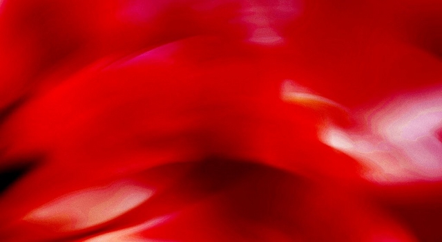 Abstract wide banner image of a deep red background with soft swirling light patterns, transitioning to lighter pink and orange tones on the right side. No people, text, or objects are present in the image.