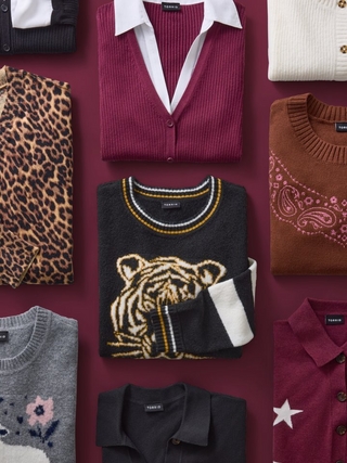Overhead flat lay of folded clothing items arranged in a grid against a dark maroon background. Items include a leopard print cardigan, a burgundy button-up vest layered over a white collared shirt, a cream cable knit sweater, a black sweater featuring a tiger graphic with folded white sleeves, a brown sweater with paisley print detailing, a gray sweater with an embroidered floral design, a black button-up shirt, and a burgundy sweater with a white star graphic. No people or text appear in the image.