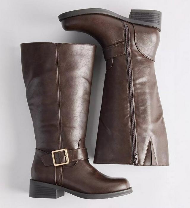 A pair of dark brown knee-high boots arranged on a plain white background, one standing upright and the other lying on its side to show the inner face. The upright boot has a smooth faux leather shaft with a center seam, a wide buckled strap with a gold-tone square buckle at the ankle, a rounded toe, and a low stacked block heel. The boot on its side shows a full-length zipper running up the inner shaft with a metal pull, a small slit at the top edge, and a stitched tab at the calf.