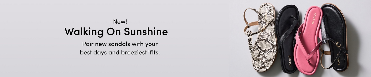 'A wide promotional banner with a light gray background featuring four sandals laid flat in a row viewed from above. From left to right: a white and gray snakeskin print slingback sandal, a black thong flip flop sandal with a Torrid branded footbed, a pink thong sandal with a Torrid branded footbed, and a black leather sandal with a gold buckle detail and a tan sole. Overlaid in white text reads New! Walking On Sunshine, with smaller white text below reading Pair new sandals with your best days and breeziest 'fits.'