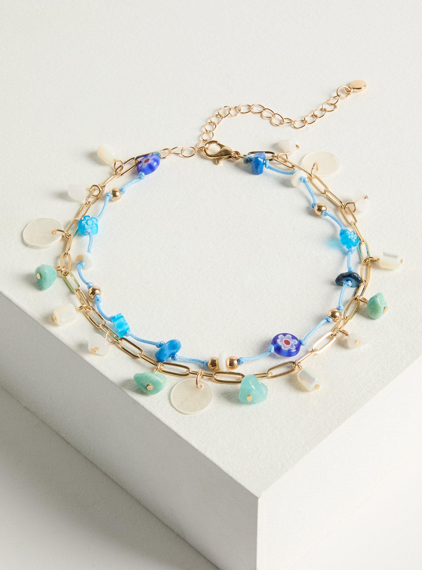 A plus-size gold-chain and blue-string anklet with turquoise, white, and blue flower beads